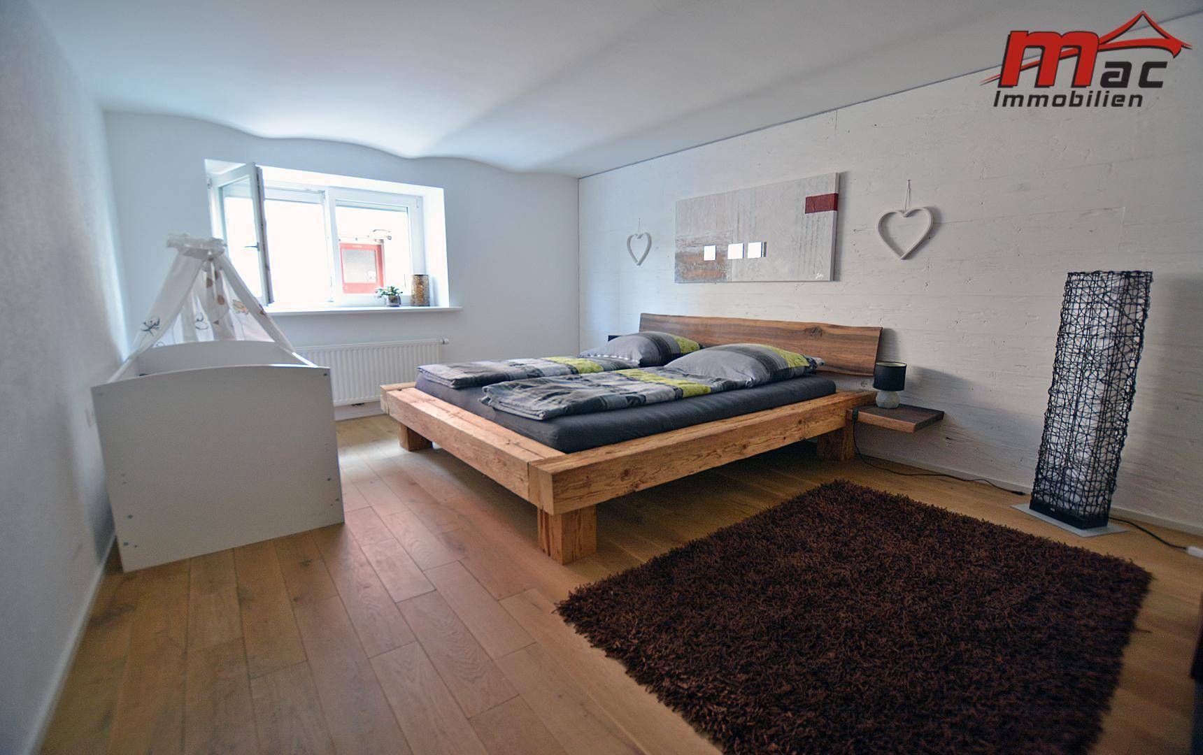 Helles Schlafzimmer mit Holzbett und Parkettboden, modern eingerichtet.