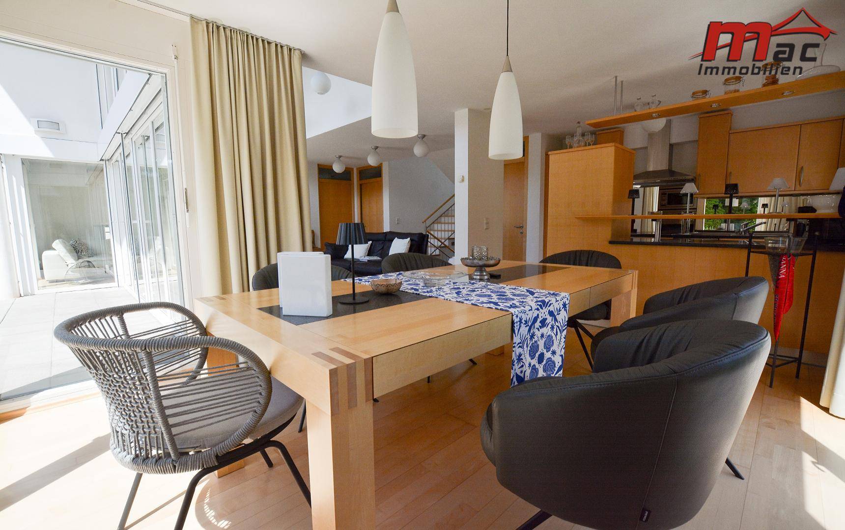 Essbereich mit Holztisch, modernen Stühlen und direktem Zugang zur Terrasse und zum Garten.