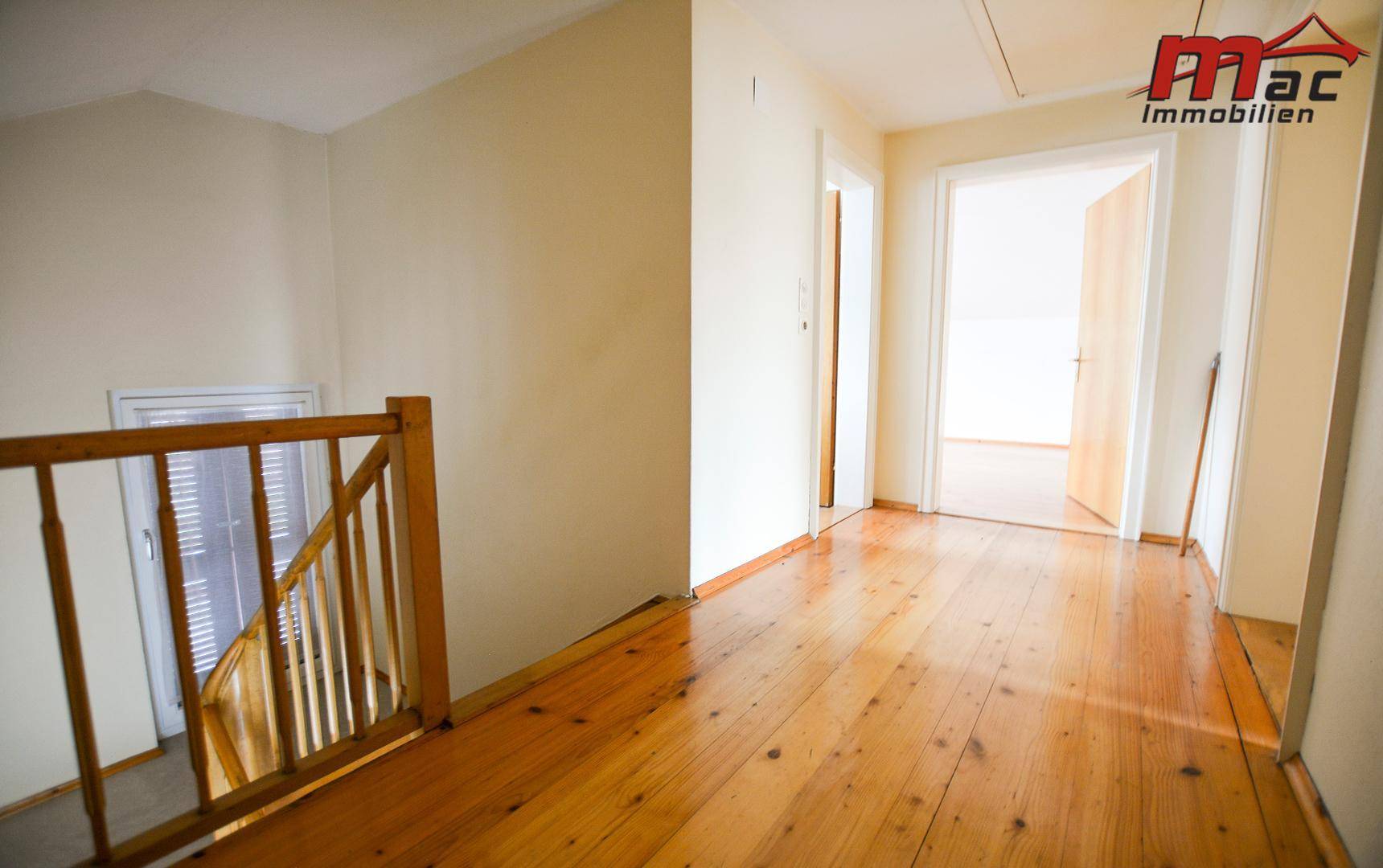 Heller Flur im Obergeschoss mit Holzfußboden und Blick auf die Treppe.