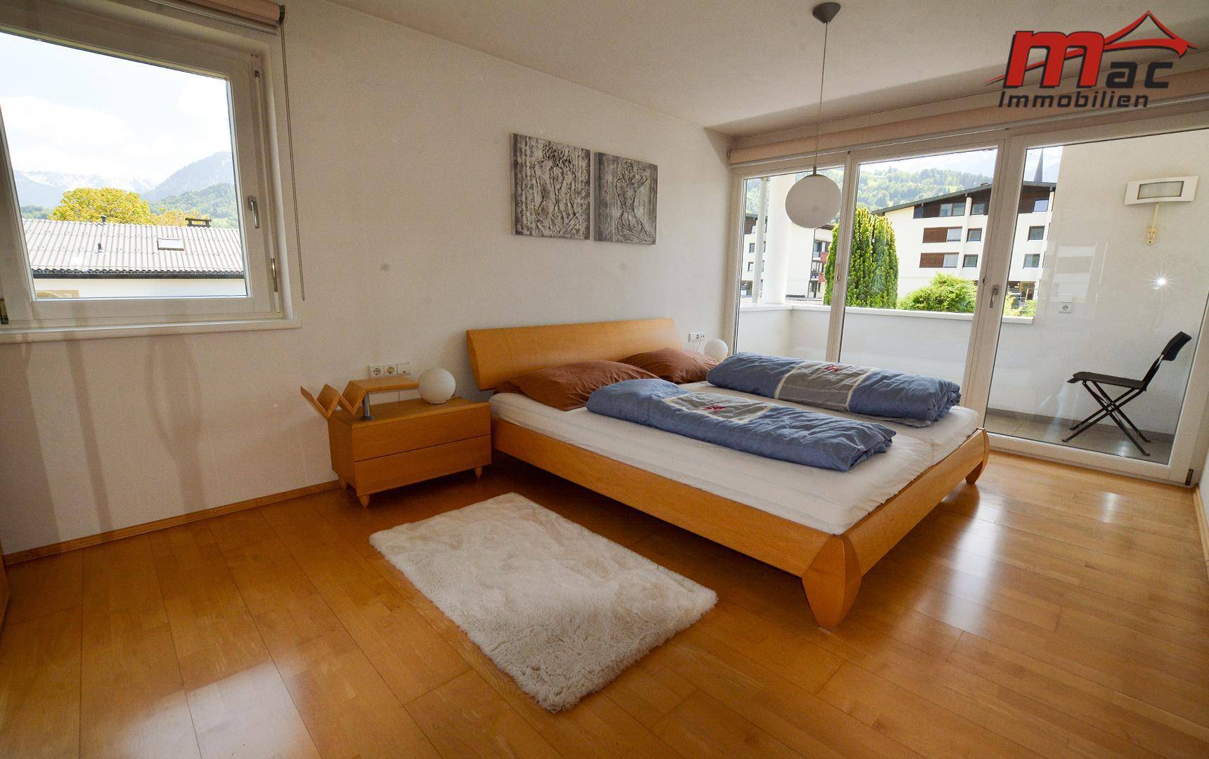 Gemütliches Schlafzimmer mit Holzbett, Parkettboden und direktem Zugang zum Balkon.