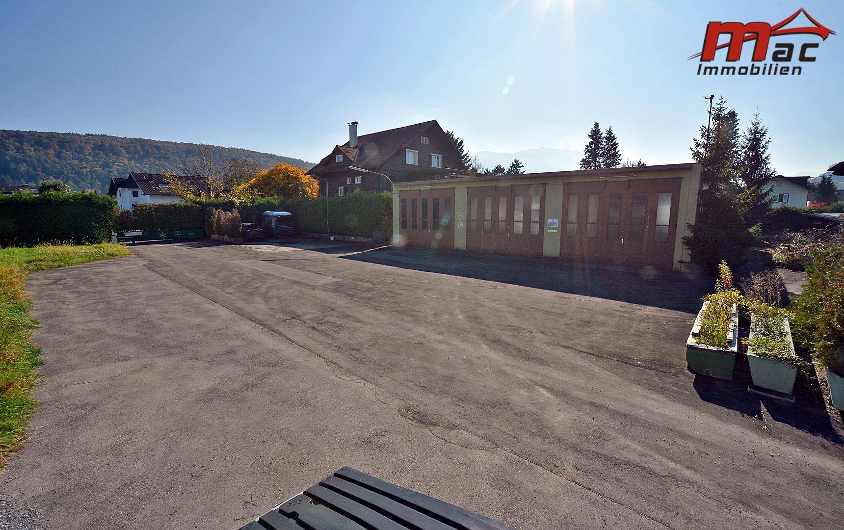 Weitläufige asphaltierte Fläche, ideal für Parkplätze, neben einem Nebengebäude unter blauem Himmel.