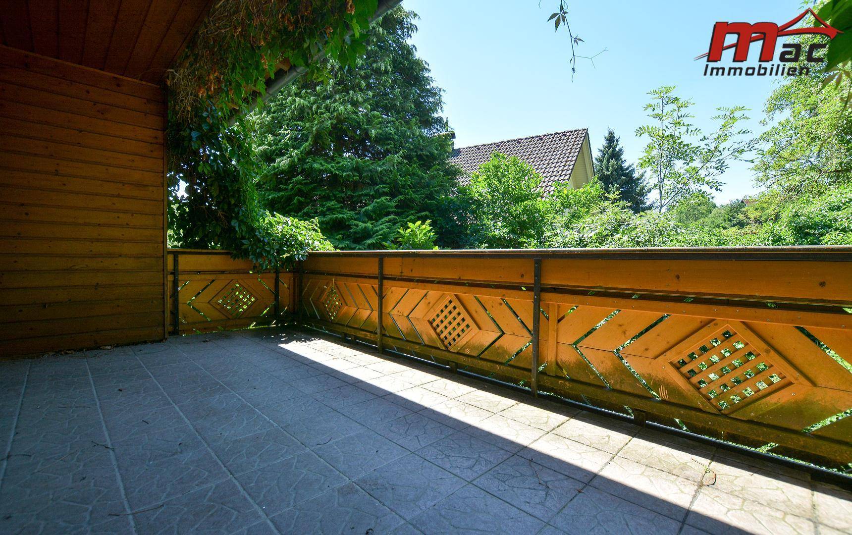 Geräumiger Balkon mit Fliesenboden und traditionellem Holzgeländer, bietet einen Blick ins Grüne.