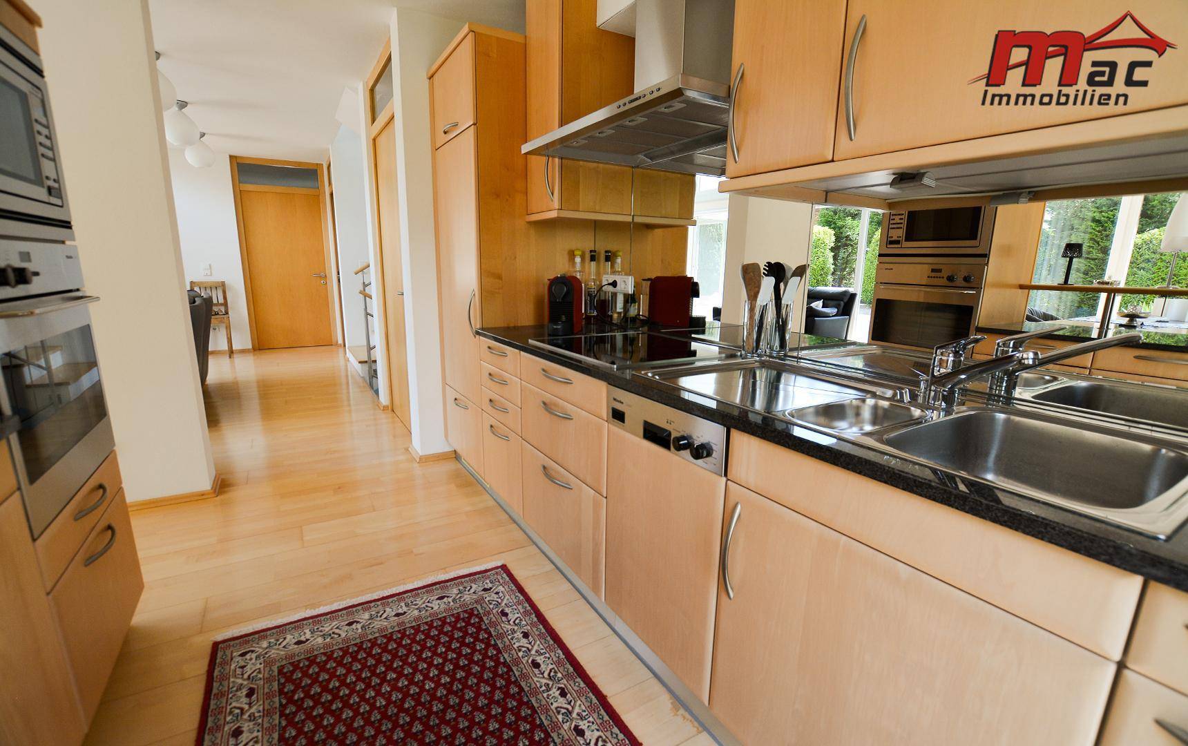 Gut ausgestattete Küche mit Holzfronten, Granitarbeitsplatte und modernen Einbaugeräten.