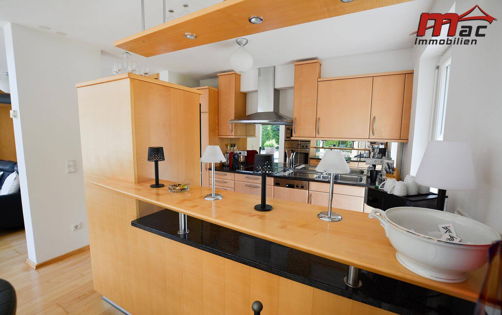 Moderne Holzküche mit Granitarbeitsplatte, Frühstücksbar und integrierten Geräten.