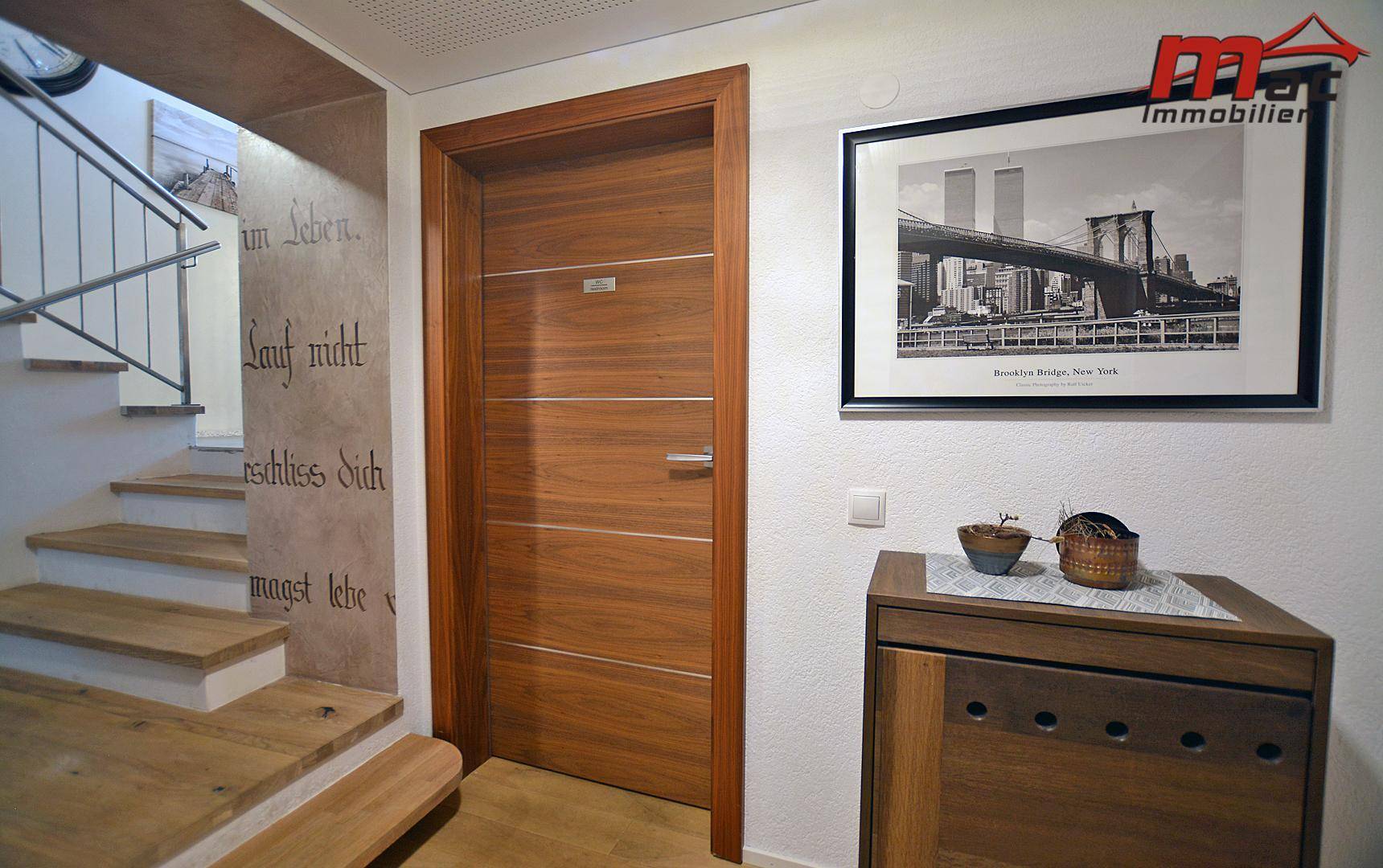 Heller Flur mit Holztür und Treppenaufgang, modern und einladend.