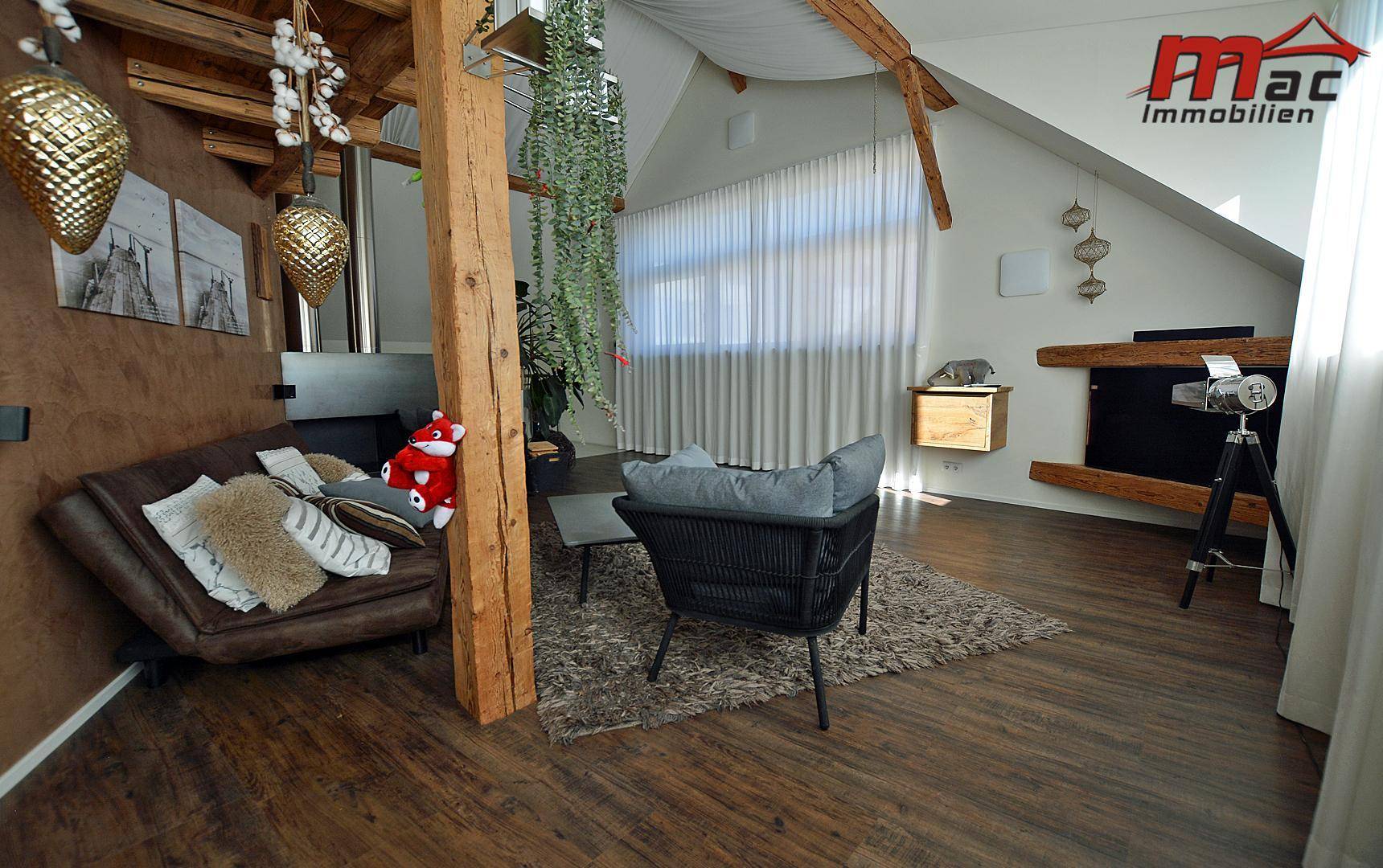 Gemütliches Wohnzimmer mit Holzbalken, dunklem Sofa und modernem Couchtisch.