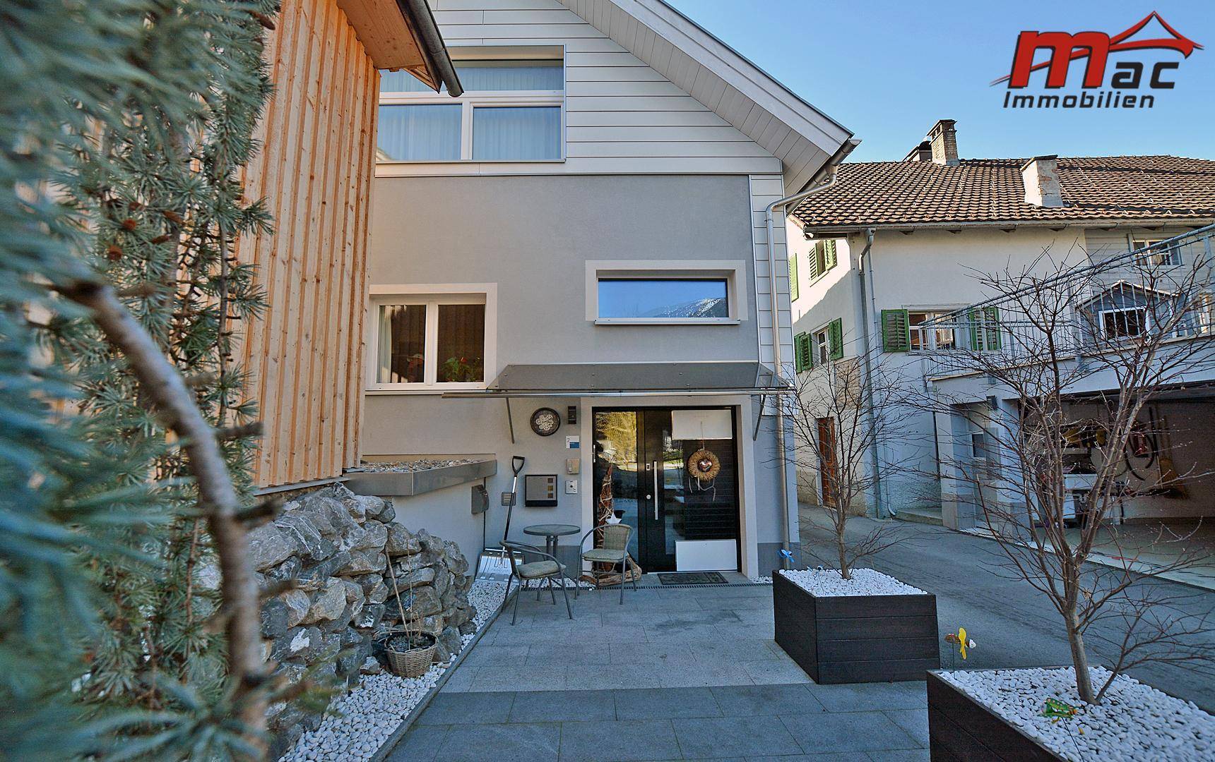 Moderne Hausfassade mit gepflegtem Eingangsbereich und kleiner Terrasse.