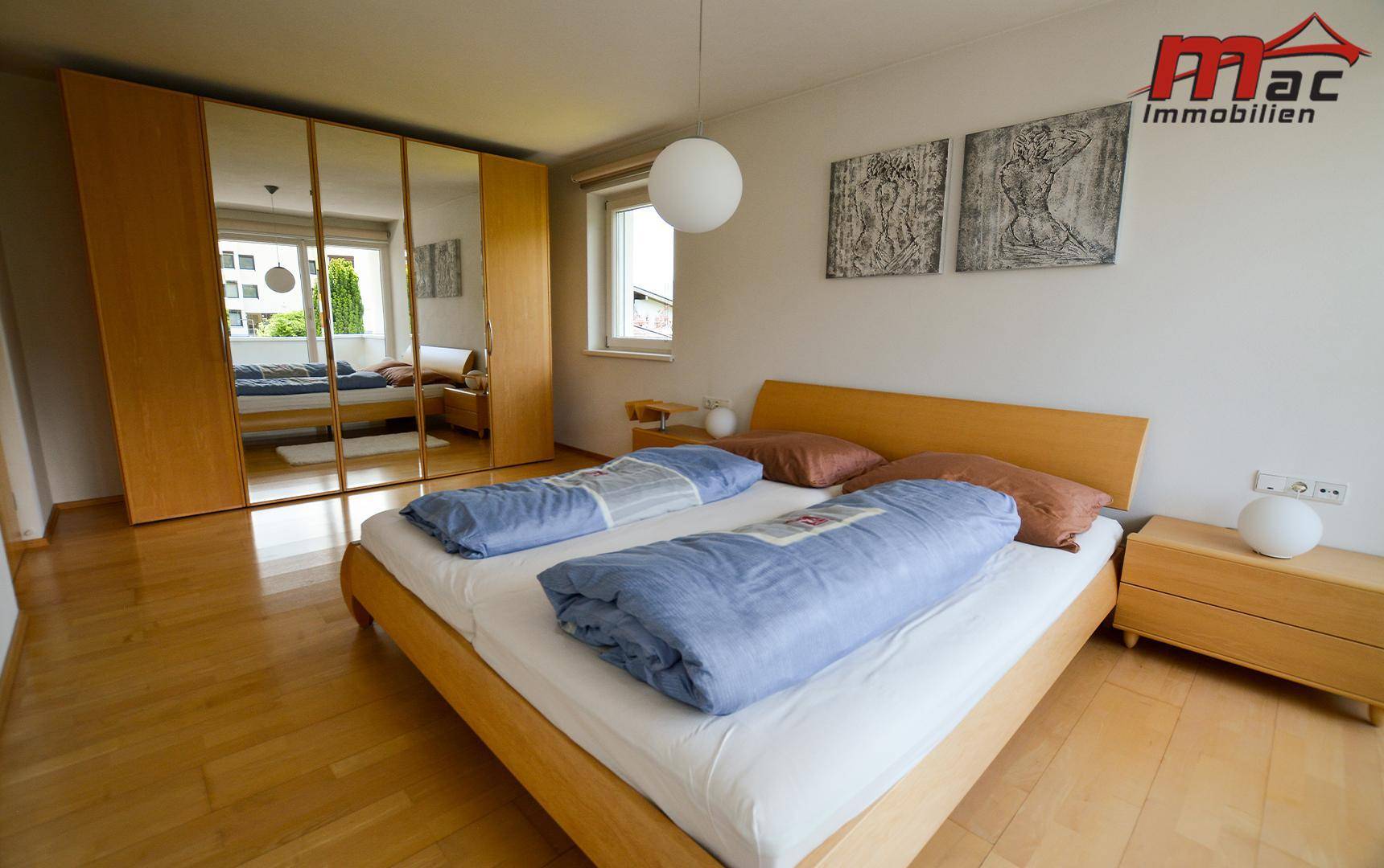 Helles Schlafzimmer mit Holzbett, Parkettboden und großem Spiegelschrank.