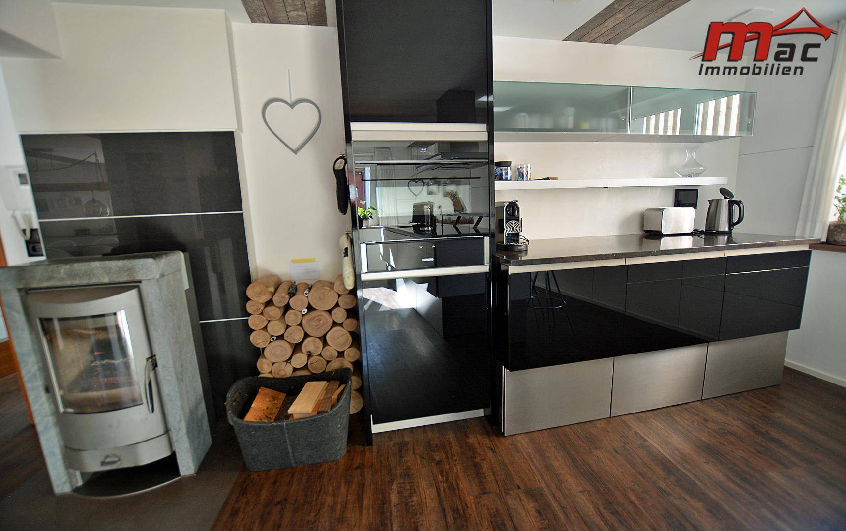 Moderne Küche mit Holzofen und integrierten schwarzen Schränken.