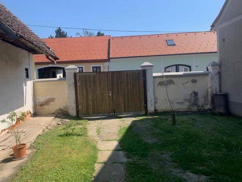 Einfacher Gartenbereich mit Rasenfläche und Holztor, umgeben von einer niedrigen Mauer.
