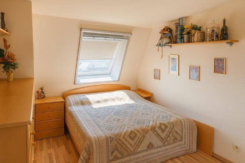 Helles Schlafzimmer mit Doppelbett, Holzmöbeln und einem Dachfenster für natürliches Licht.