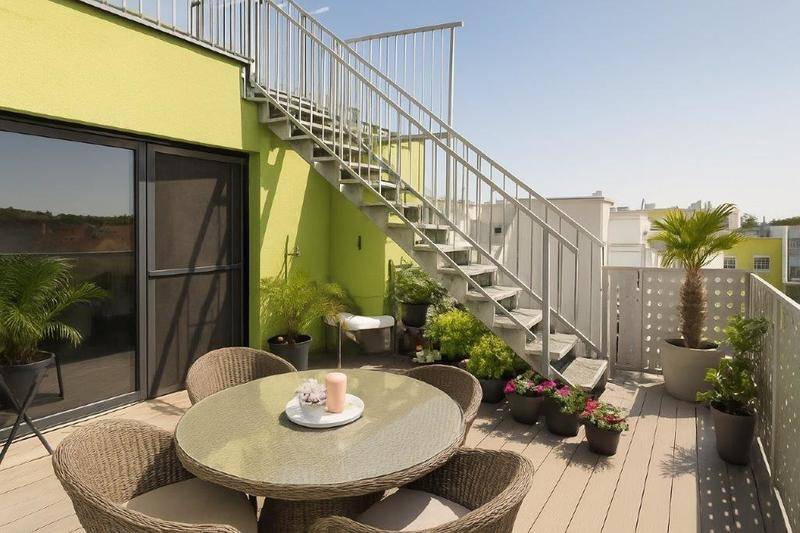 Geräumige Dachterrasse mit Sitzgelegenheiten, Pflanzen und einer Außentreppe zu einer weiteren Ebene.