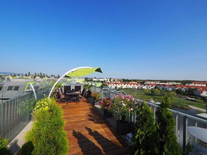 Weitläufige Dachterrasse mit Holzboden, Sitzbereich und Panoramablick über die Umgebung.