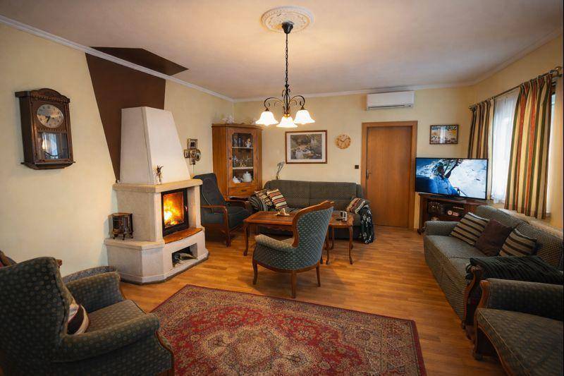 Wohnzimmer mit Kamin, bequemen Sofas, Holzboden und einem Teppich.