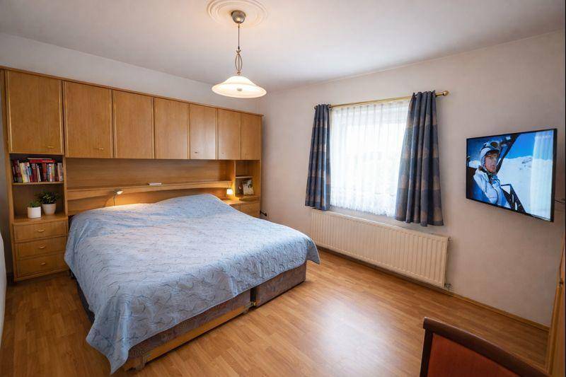 Schlafzimmer mit Einbauschränken über dem Bett, Holzboden und einem Fenster.