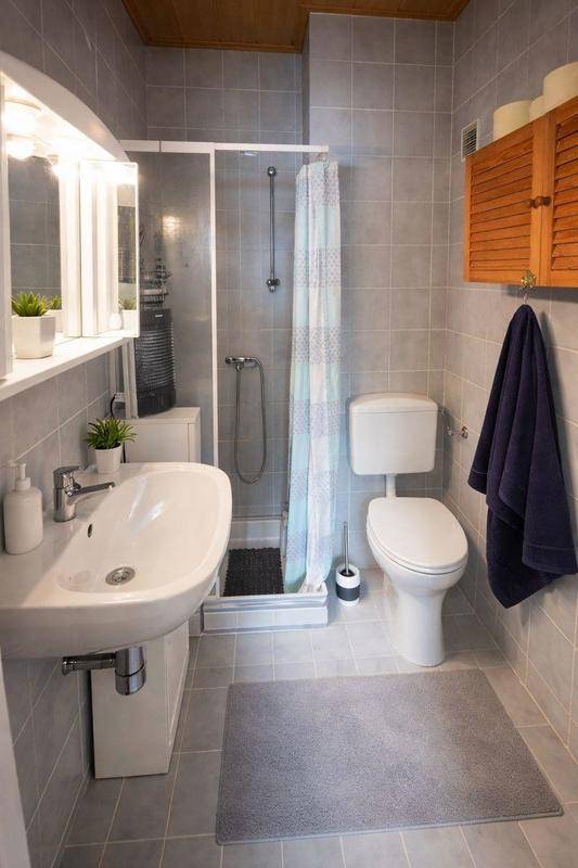 Kleines Badezimmer mit Dusche, WC, Waschbecken und hellen Fliesen.