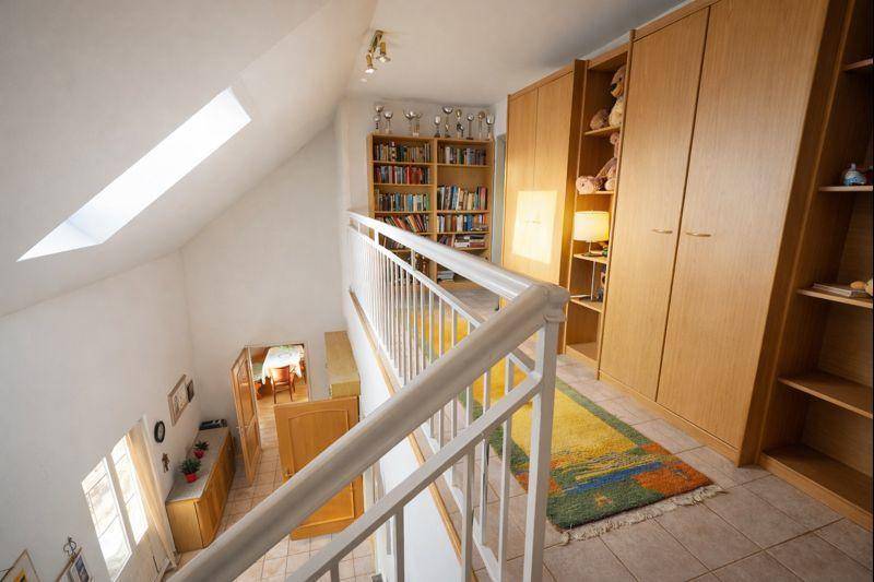 Heller Flur im Dachgeschoss mit Bücherregalen, Einbauschränken und Dachfenster.