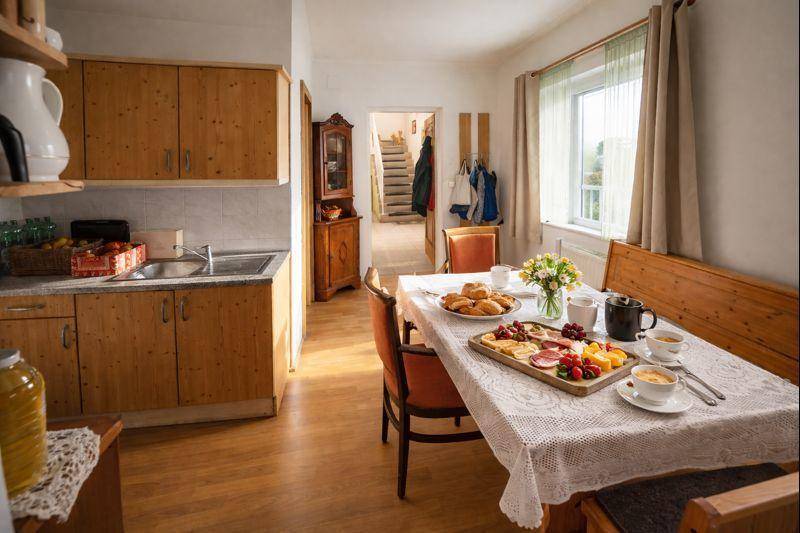 Gemütliche Wohnküche mit Holzeinbauten, Esstisch und Blick in den Flur.