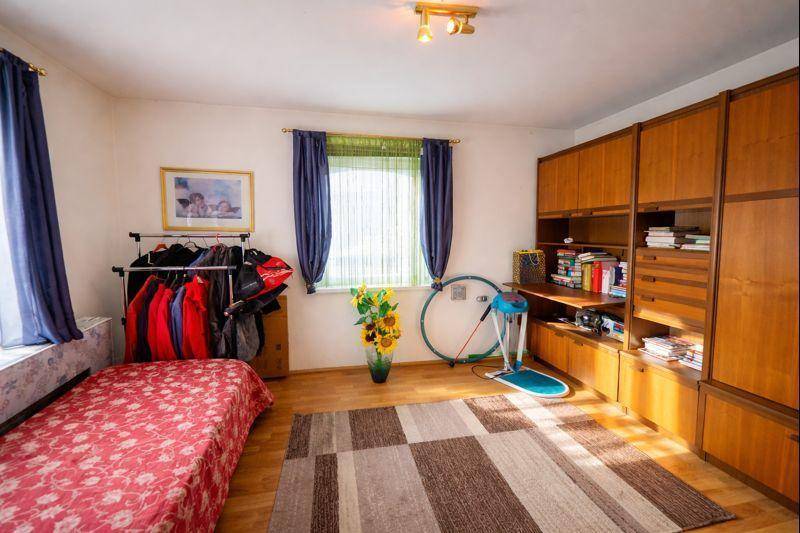 Helles Zimmer mit Holzboden, Kleiderstange und einem großen Schrank.