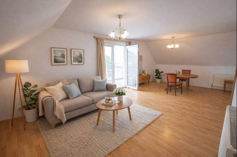Geräumiges Wohnzimmer im Dachgeschoss mit Balkonzugang, Holzboden und moderner Einrichtung.