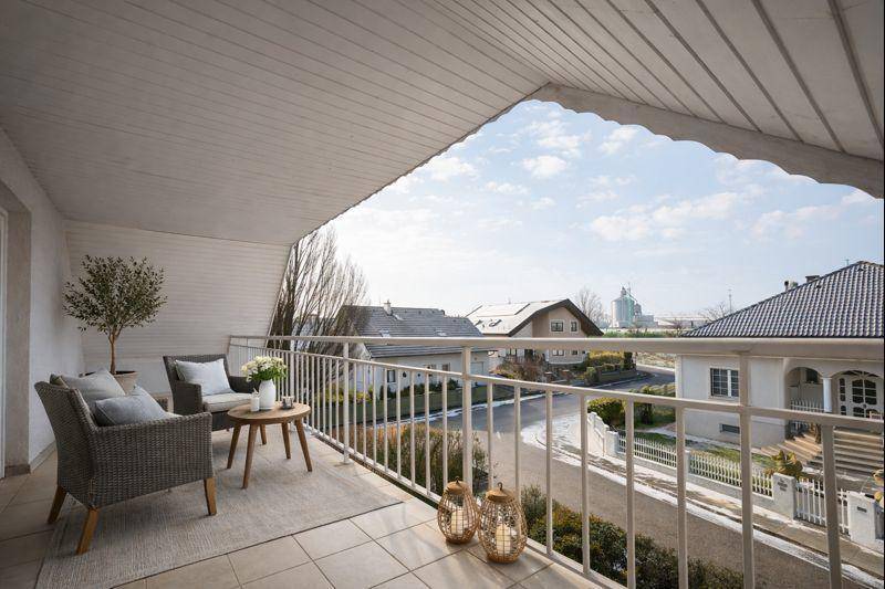 Überdachter Balkon mit Sitzgelegenheiten und Blick auf die umliegende Nachbarschaft.