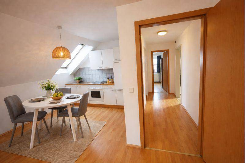 Offene Küche im Dachgeschoss mit Essbereich, weißen Schränken und Dachfenstern.