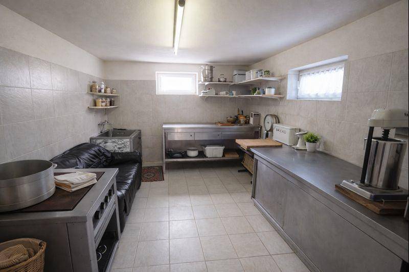 Kellerraum mit Fliesenboden, Arbeitsflächen aus Edelstahl und kleinen Fenstern.