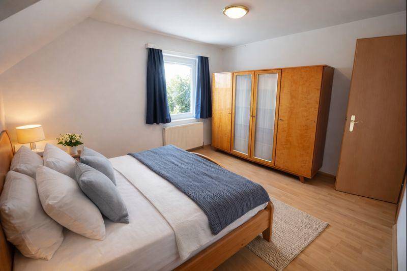 Schlafzimmer im Dachgeschoss mit Holzboden, großem Kleiderschrank und Fenster.