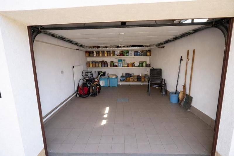Geräumige Garage mit Fliesenboden, Regalen und viel Stauraum für Fahrzeuge und Haushaltsgegenstände.