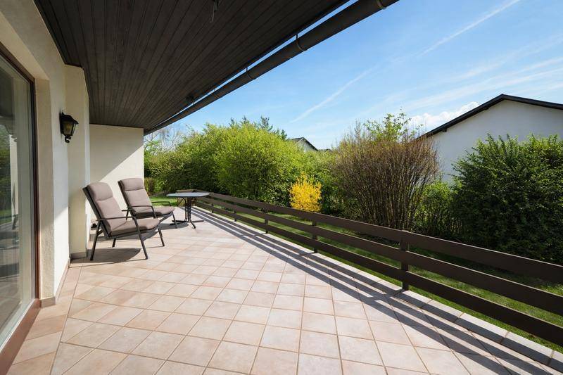 Heller Balkon mit Fliesenboden, Sitzgelegenheiten und einem angenehmen Blick ins Grüne.