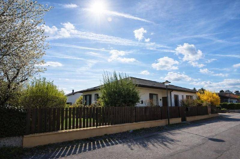 Einfamilienhaus mit gepflegtem Vorgarten, Zaun und sonnigem Himmel, einladend und gut erhalten.