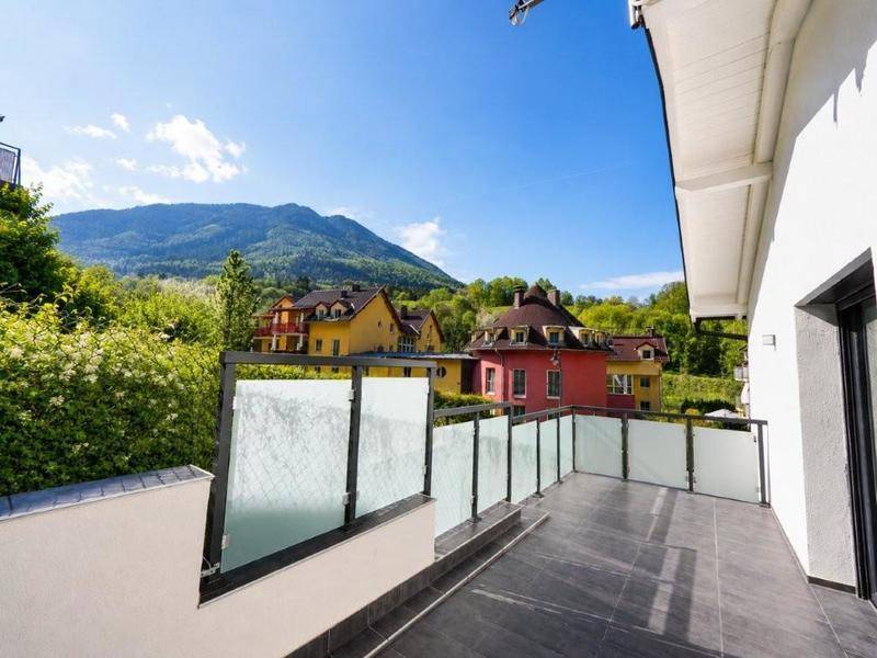 Großer Balkon mit Fliesenboden und Glasgeländer, bietet einen weiten Panoramablick auf die Berge.