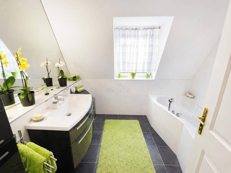 Modernes Badezimmer mit Eckbadewanne, Einzelwaschbecken und Dachschräge unter einem Fenster.