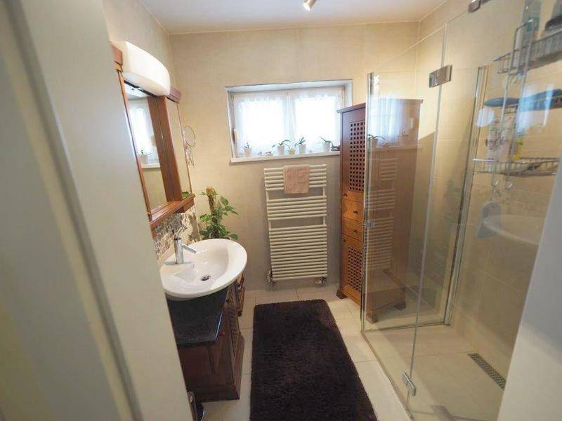 Funktionales Badezimmer mit Duschkabine, Einzelwaschbecken und beheiztem Handtuchhalter neben einem Fenster.