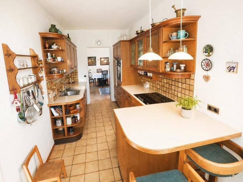 Traditionelle Holzküche mit Fliesenboden, integrierten Geräten und Frühstücksbar.