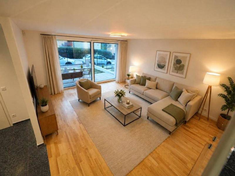 Geräumiges Wohnzimmer mit hellem Parkettboden, gemütlicher Sitzecke und Zugang zur Terrasse.