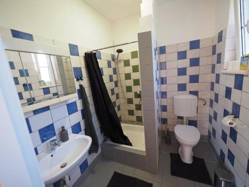 Badezimmer mit auffälligen blau-weißen Fliesen, Dusche und Fenster für Tageslicht.