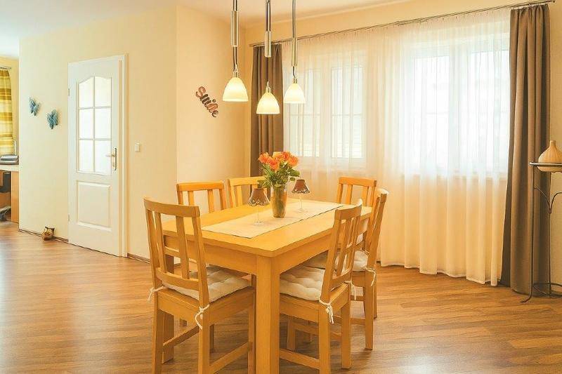 Heller Essbereich mit Holztisch, passenden Stühlen und großen Fenstern.