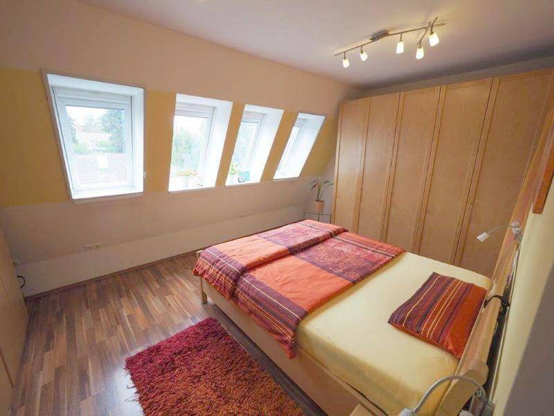 Gemütliches Schlafzimmer im Dachgeschoss mit Holzboden und Dachfenstern.