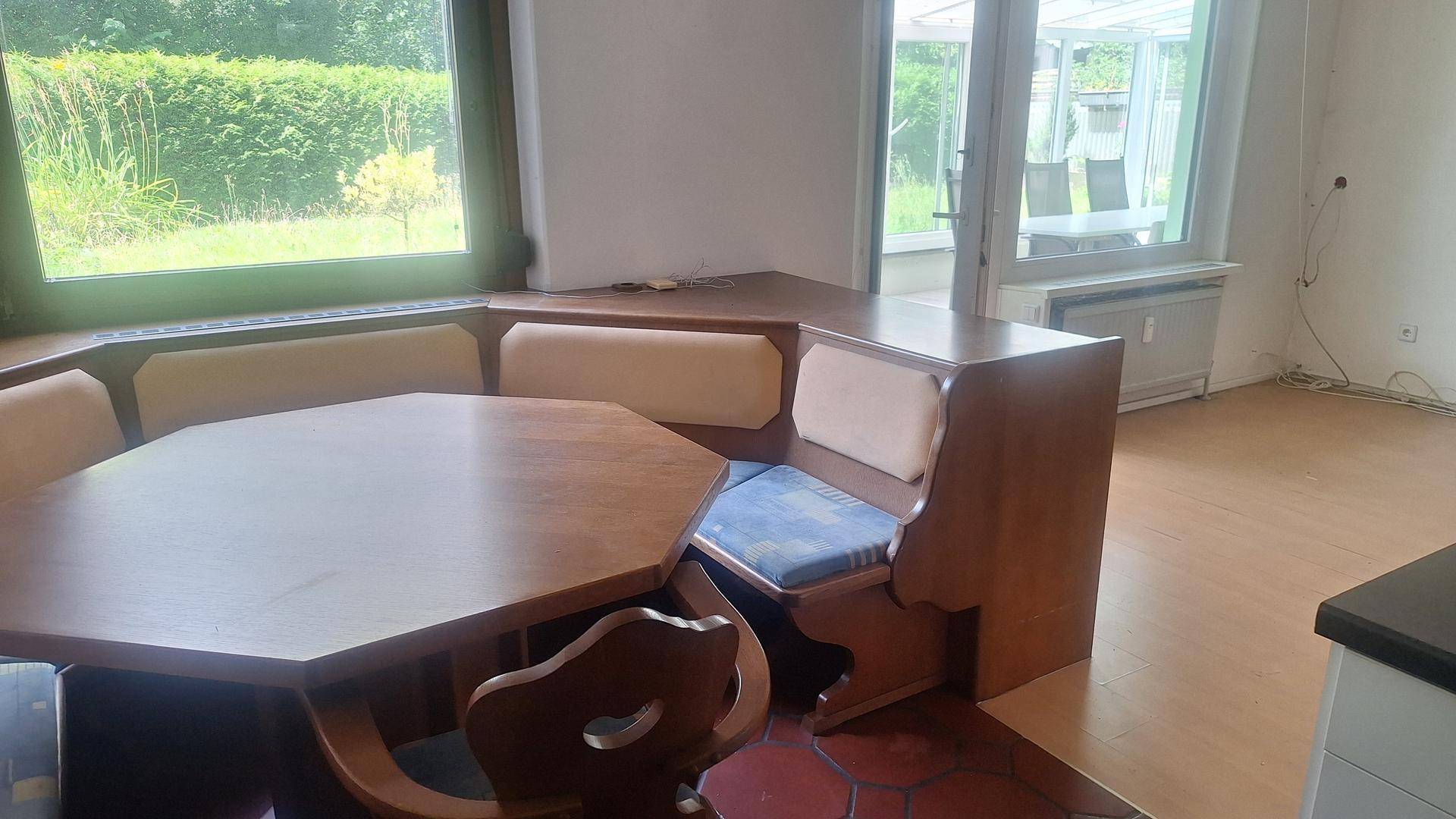Rustikaler Essbereich mit Holzeckbank und Tisch, angrenzend an den Wintergarten mit viel Licht.