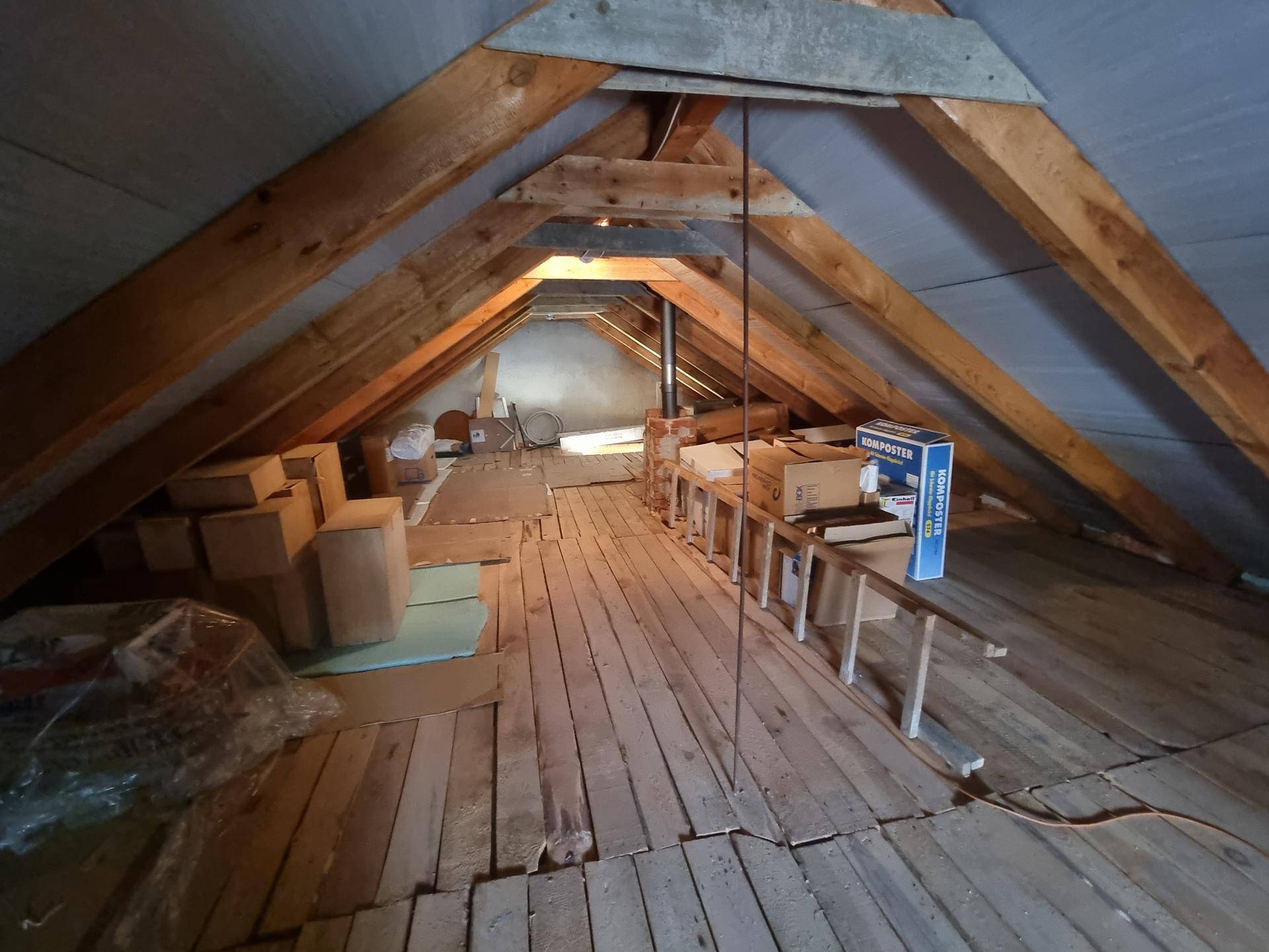 Weitläufiger Dachboden mit Holzboden und Stauraum, unter dem sichtbaren Dachstuhl.
