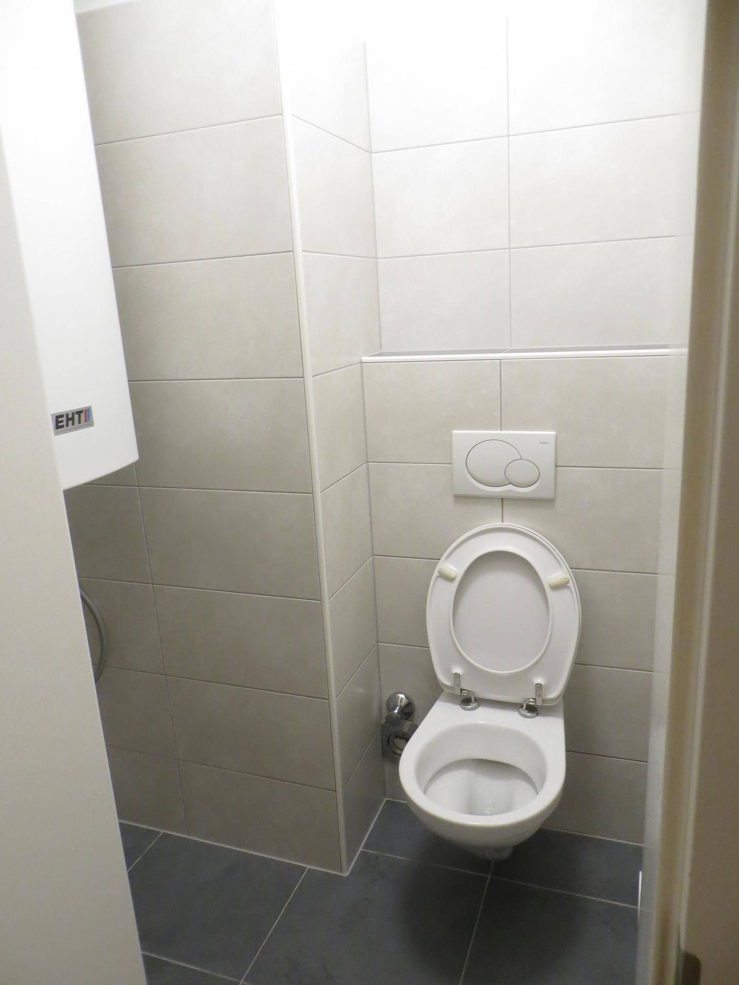 Separates WC mit Wand-WC und hellen Fliesen, praktisch und funktional gestaltet.