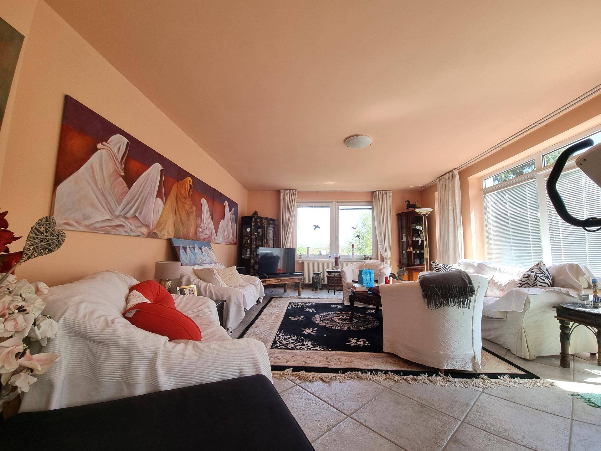 Helles Wohnzimmer mit bequemen Sofas, großem Wandbild und Blick ins Grüne durch die Fenster.