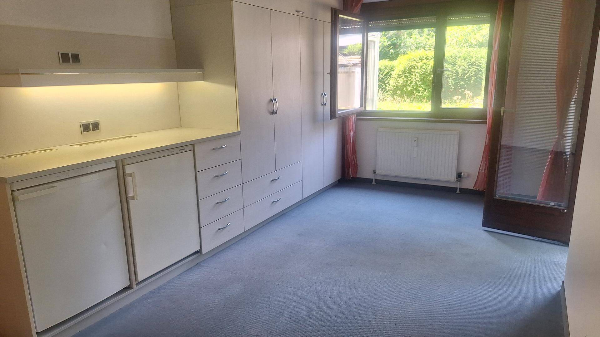 Geräumiges Zimmer mit Einbauschränken und Teppichboden, bietet viel Stauraum und Blick ins Grüne.