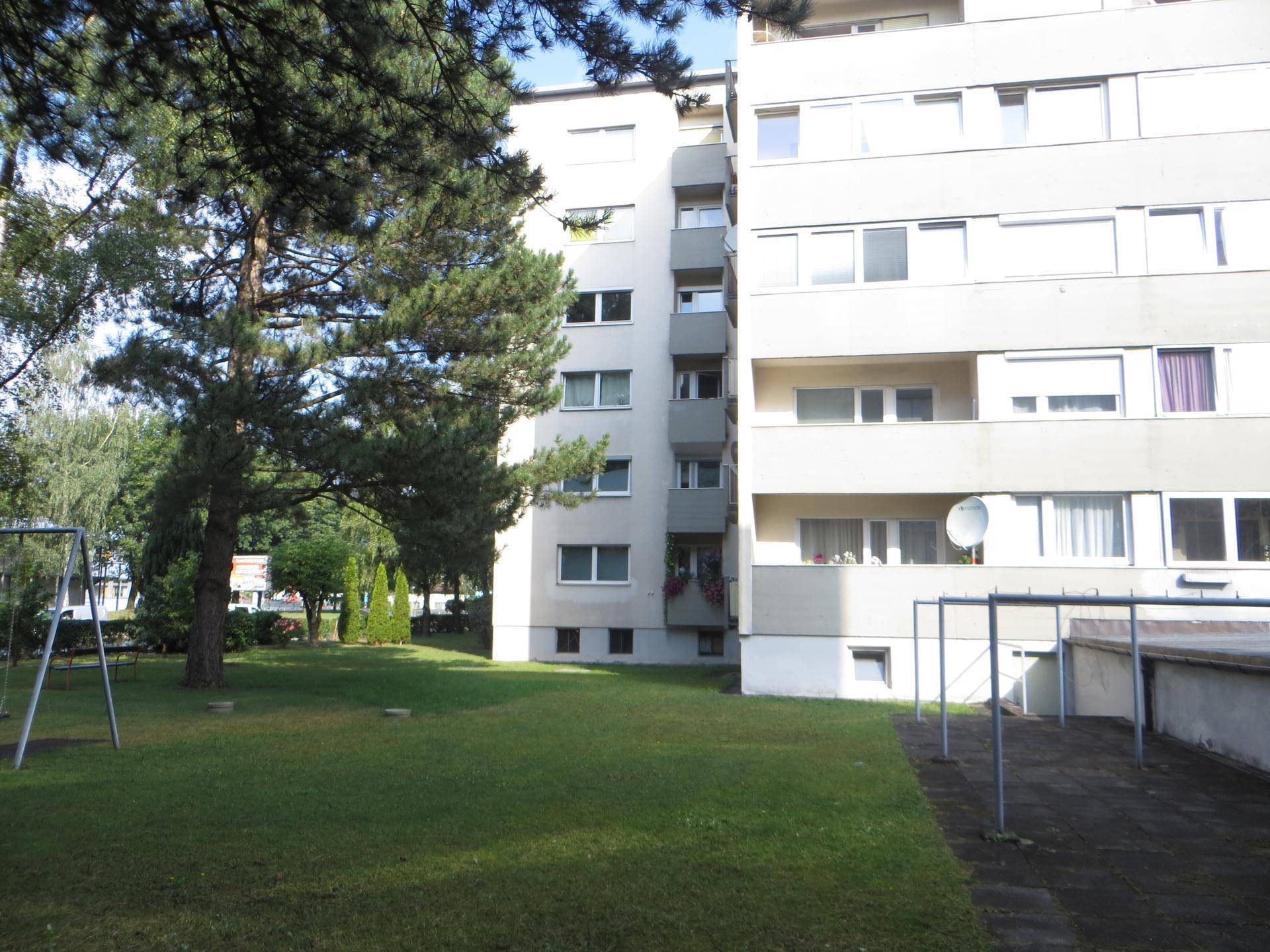 Große Grünfläche mit Spielgeräten und Bäumen, ideal für Familien und Kinder.