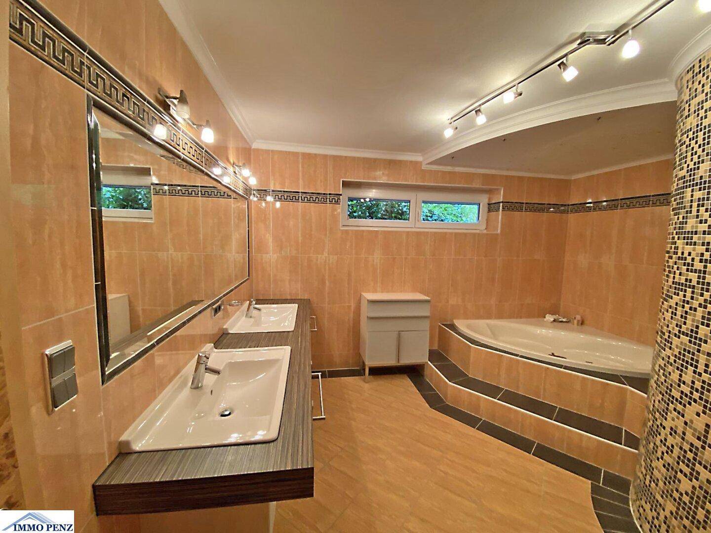 Geräumiges Badezimmer mit Eckbadewanne, Doppelwaschbecken und dekorativen Fliesen im 80er-Jahre-Stil.