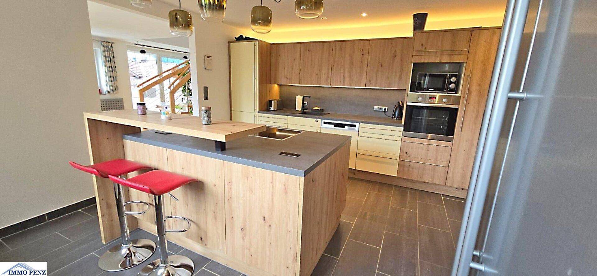Moderne Holzküche mit Kücheninsel, Frühstücksbar und integrierten Geräten.