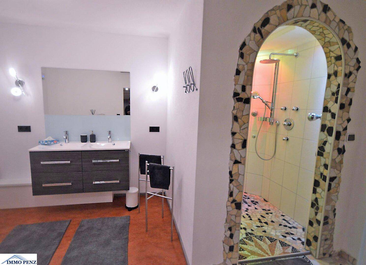 Modernes Badezimmer mit Doppelwaschbecken und einer einzigartigen Dusche mit Mosaikfliesen.