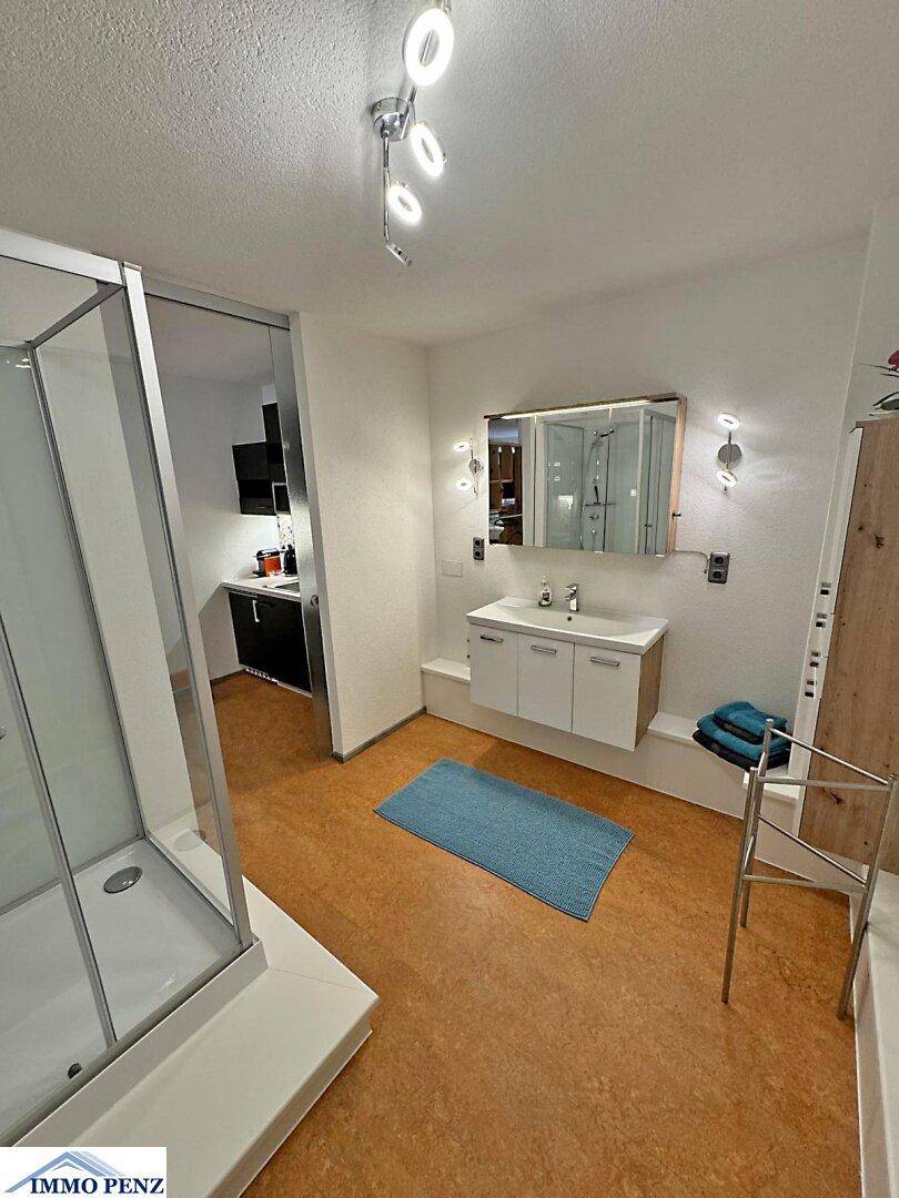 Helles Badezimmer mit Duschkabine, Einzelwaschbecken und beheiztem Handtuchhalter.
