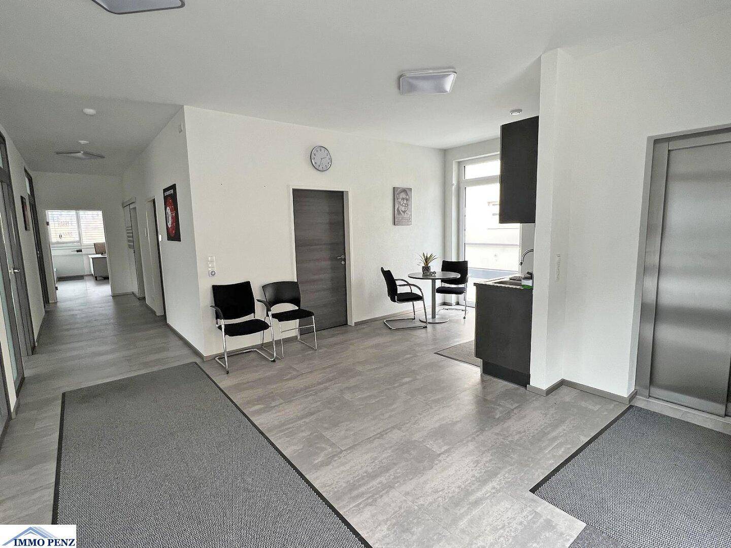 Empfangsbereich oder Flur mit Sitzgelegenheiten, modernen Türen und Zugang zu verschiedenen Büroräumen.